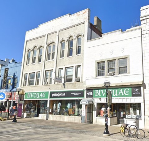A white building with a green awning that says Bivouac.